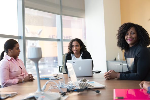Three women at meeting with two MacBooks