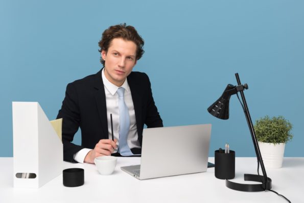 A business man sitting at his desk in front a laptop