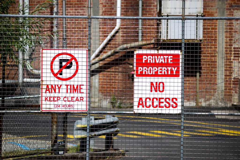 Private property no access sign behind wire fence