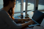 Woman typing on a MacBook in front of an open window