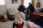 Woman working from home seated a laptop while child watches
