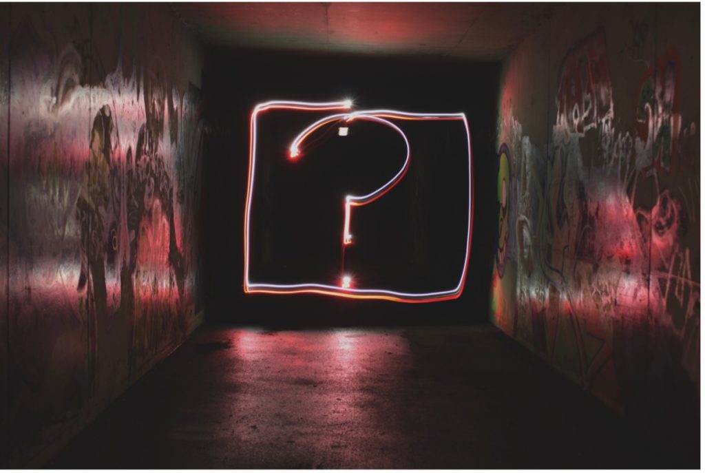Glowing question mark in a dark graffitied hall